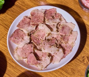 흰 접시에 썬 삶은 돼지고기에 깨를 뿌린 모습